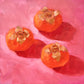 original oil painting of three orange persimmons on soft pink with strong shadows