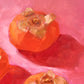 original oil painting of three orange persimmons on soft pink with strong shadows