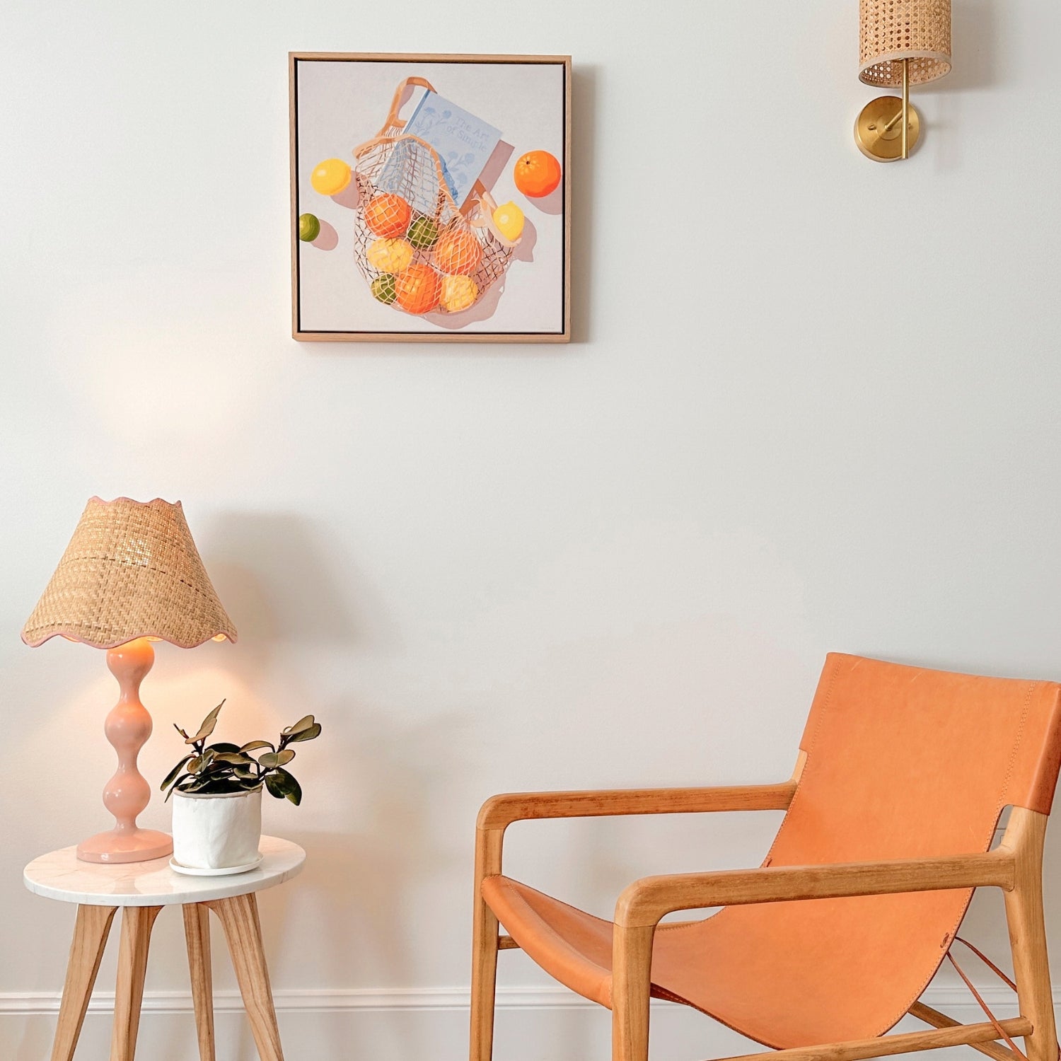 modern and contemporary fine art canvas print of an original oil painting of colorful citrus fruits like lemons, orange and limes, in a string/net bag with a light blue diary reading the art of simple. The fruits, bag and diary are on a white background with strong shadows