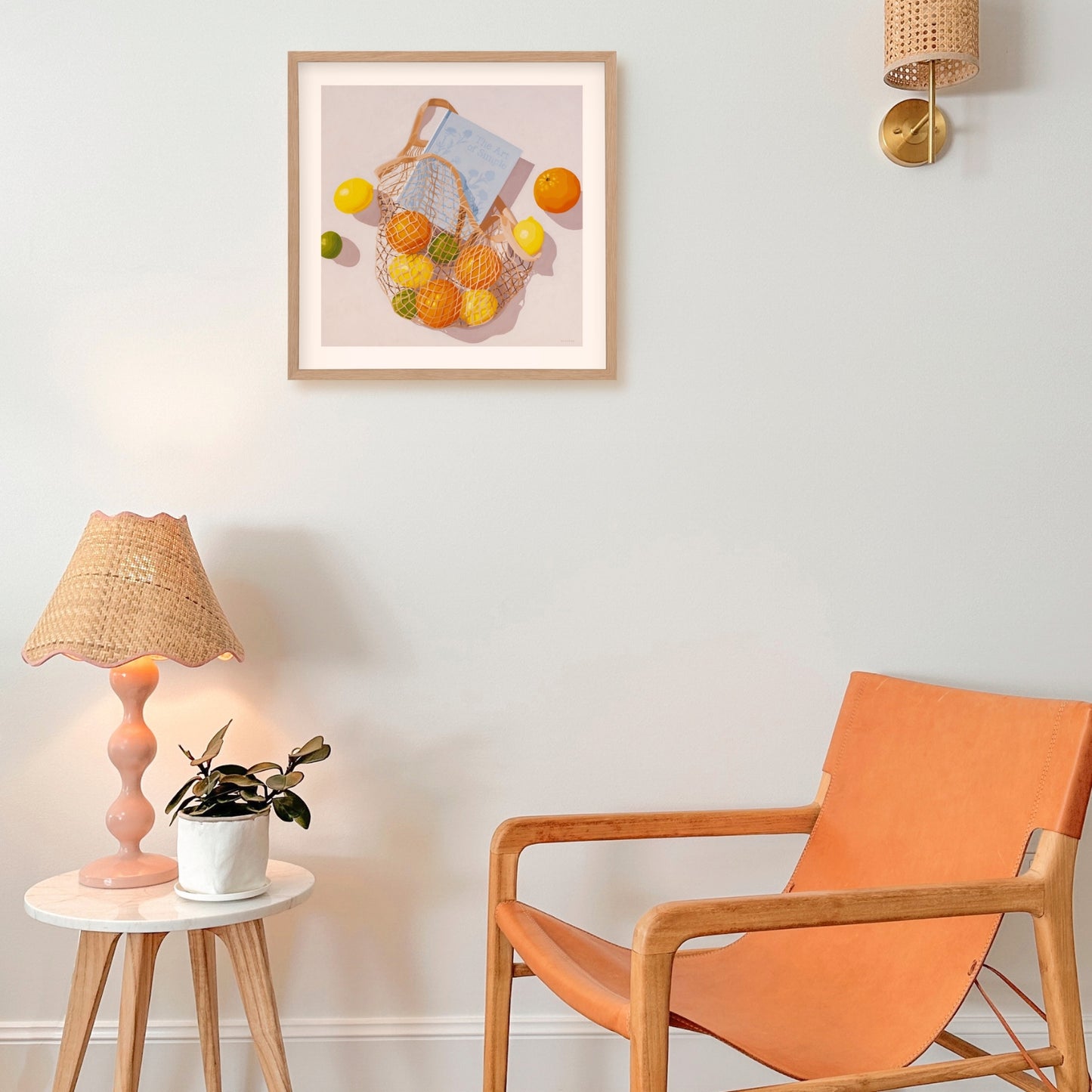 modern and contemporary fine art paper print of an original oil painting of colorful citrus fruits like lemons, orange and limes, in a string/net bag with a light blue diary reading the art of simple. The fruits, bag and diary are on a white background with strong shadows